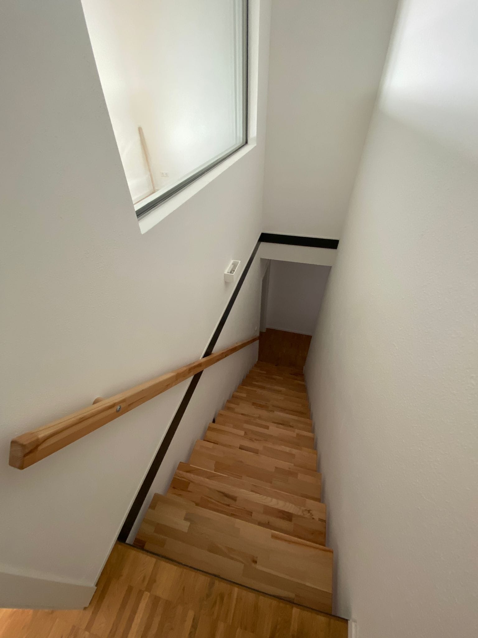 Renovierter Treppenaufgang mit verglaster Trockenbauwand und Holzhandlauf